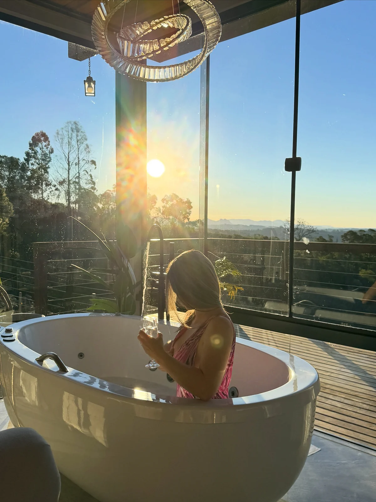 Hóspede apreciando o pôr do sol na hidromassagem da cabana