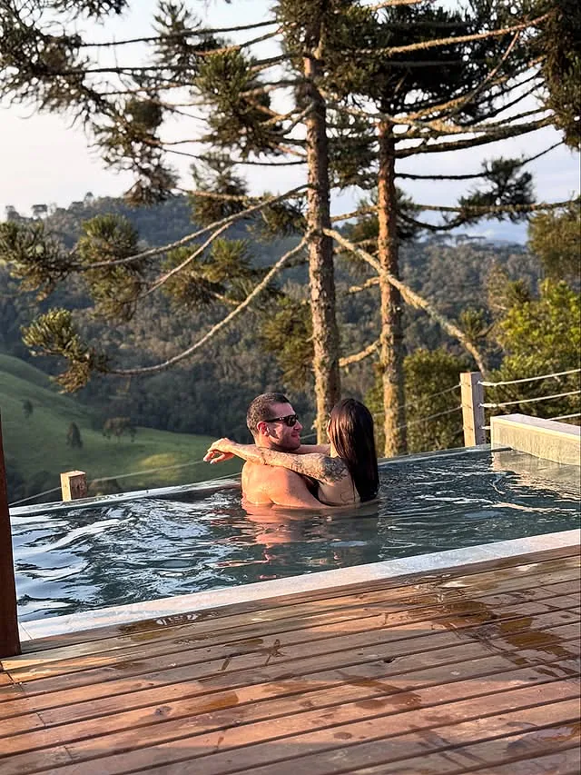 Casal abraçado na piscina aquecida com montanhas ao fundo